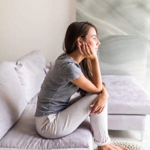 Young pretty woman sitting on the couch and thinking Young woman sitting on the couch and thinking